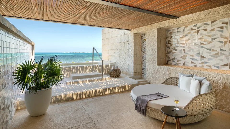 Covered terrace with a plunge pool up steps, round wicker daybed, geometric white-and-grey tiles and a turquoise sea view. A plunge-pool terrace, not a 'Deluxe Ocean View Suite' (no such category); consistent with INSPIRA ocean-front categories.