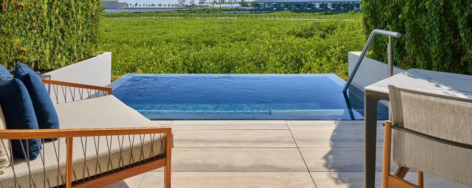 Private terrace plunge pool with wood-and-rope outdoor seating, looking over the mangrove toward resort buildings